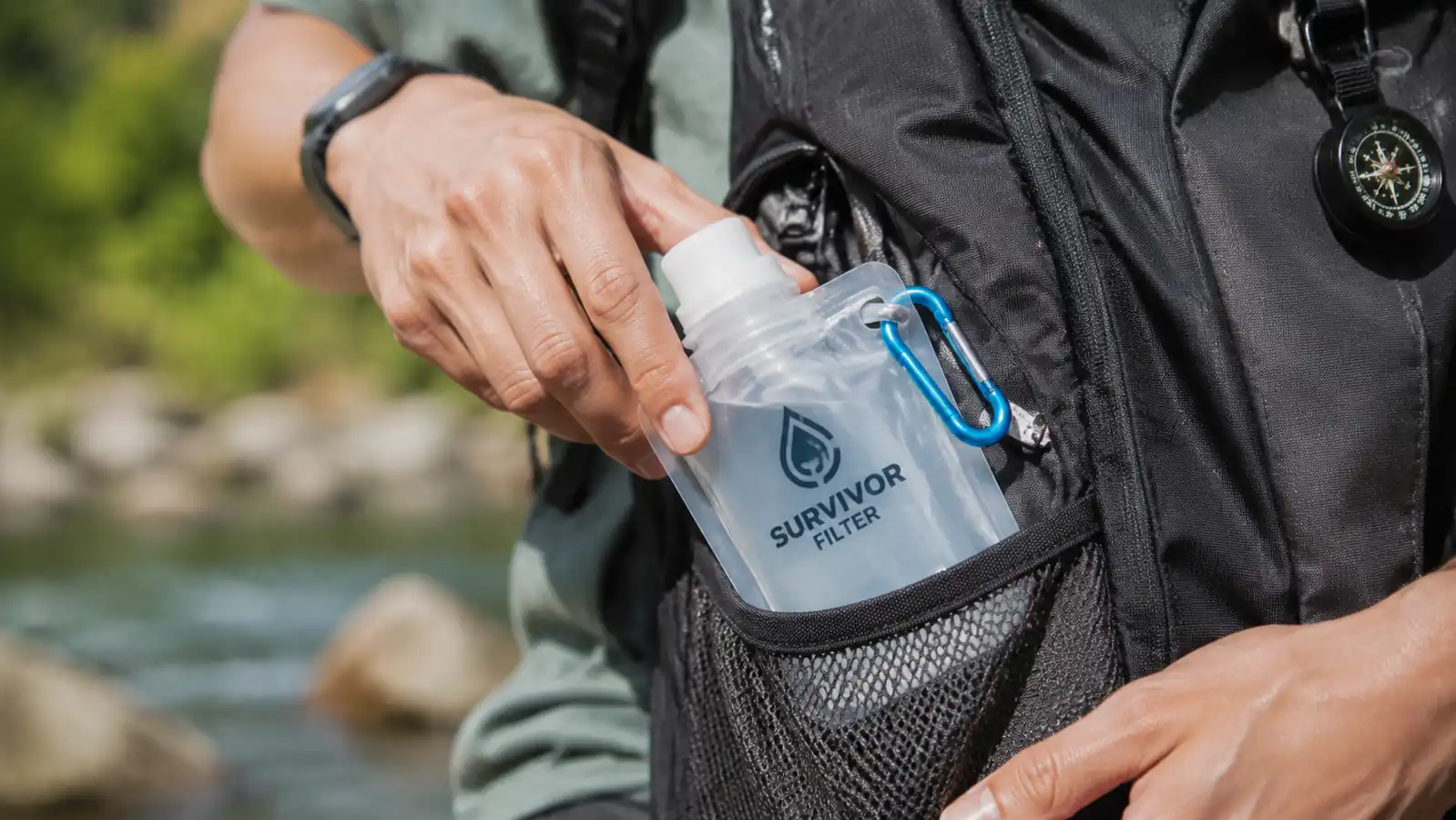 Hand folding a clear collapsible water bottle down to a flat disc before packing it into a backpack side pocket
